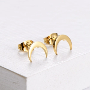 Minimalist gold moon stud earrings in polished stainless steel on white stone background