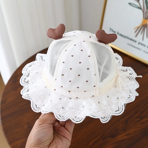 Détail d'un chapeau de soleil bébé en maille respirante, motifs cœurs et bord dentelle