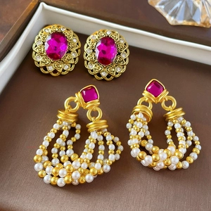 Detail of vintage earrings with rose red gems and pearls on a brown luxury tray