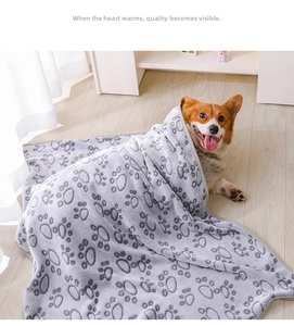 Close-up of thick grey flannel pet blanket with black paw prints on a cozy Corgi dog