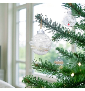 Close-up of clear Christmas ornament with white lace and hemp rope on a festive tree branch