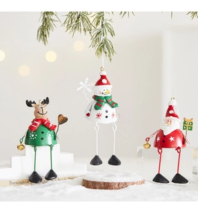 Close-up of metal Santa, snowman, and reindeer ornaments on snowy pine branches