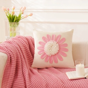 Detailed view of square pillow cover with pink floral applique on soft knit blanket