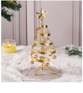 Close-up of golden iron Christmas tree with star topper and bells on snowy background