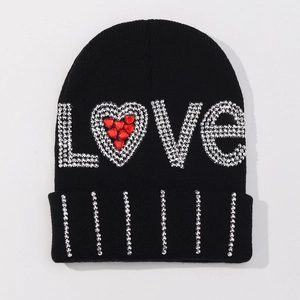 Close-up of LOVE lettering with sparkling rhinestones and a red heart on a black knit beanie