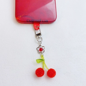 Close-up of handmade beaded red cherry charm attached to a red phone case