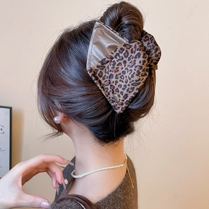 Detail of leopard print fabric and brown faux leather oversized bow hair claw clip