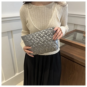 Detail of silver heart quilted texture on puffy metallic clutch and makeup bag
