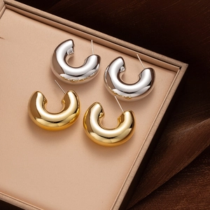 Polished gold and silver C-shaped hoop earrings displayed in a minimalist jewelry box