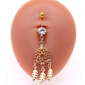 Détail du piercing de nombril doré avec pendentif attrape-rêves et pierres précieuses