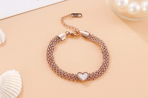 Detail of rose gold multi-strand stainless steel bracelet with a white heart charm