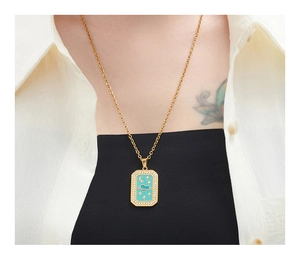 Close-up of a gold rectangle pendant with turquoise enamel and celestial star moon patterns