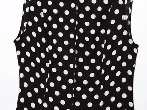 Dettaglio dello scollo dell'abito a pois senza maniche e della trama del tessuto