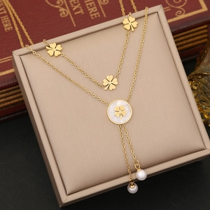 Detail of gold double-layer necklace with clover motif, mother of pearl, and pearl tassels