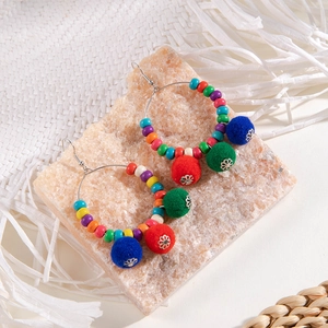 Detail view of bohemian Christmas hoop earrings with colorful wooden beads and felt pom-poms