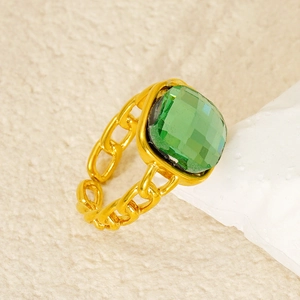 Dettaglio di un anello a catena dorato con una grande pietra quadrata verde smeraldo