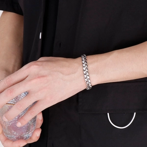 Polished silver stainless steel hip hop cuban chain bracelet on male model's wrist