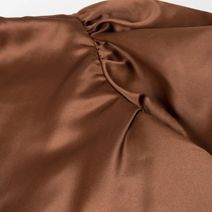 Close-up of premium brown satin fabric showing smooth texture and elegant glossy finish