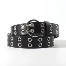 Detail of black faux leather belt featuring double-row silver metal eyelets and round buckle
