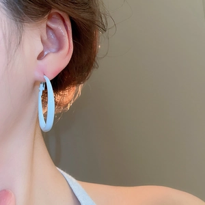 Close-up of light blue minimalist round hoop earring with polished finish on model's ear