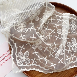 White floral embroidery lace scarf with scalloped edges in a wooden tray display