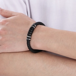 Close-up of woven black leather bracelet with silver and black metal rings on wrist
