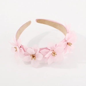 Détail d'un serre-tête rose avec fleurs en tissu montrant la texture et le cœur doré