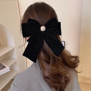 Detail of a large black velvet bow hair clip with elegant pearl and rhinestone accents