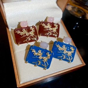 Detailed macro of red and blue enamel rectangle earrings with golden flower patterns