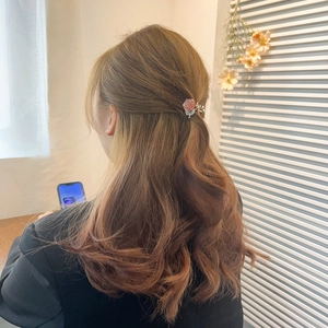 Sparkling pink flower hair claw clip securing a ponytail on a model with long wavy hair