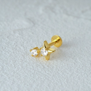 Close-up of gold star cartilage stud earring with two clear sparkling gemstones