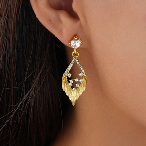 Close-up of a gold hollow leaf earring with sparkling rhinestones on a female model