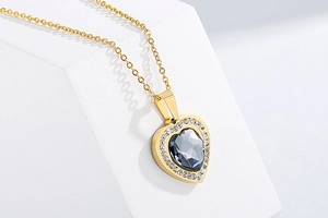 Macro shot of gold heart pendant necklace with dark grey crystal and cubic zirconia