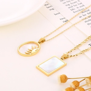 Detail van gouden ketting met holle zonnestraal hanger en wit parelmoer inlegstukje