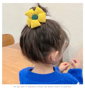 Close-up of a child wearing a yellow sunflower hair tie on a neat ponytail bun