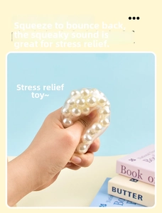 Close-up of clear squishy stress toy filled with white pearls being squeezed for stress relief