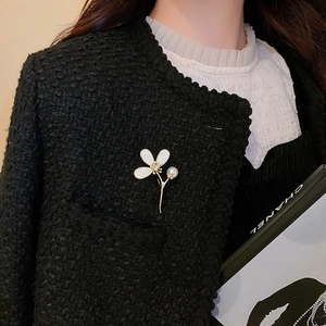 Détail d'une broche florale plaquée or avec perles et zircon sur une veste en tweed
