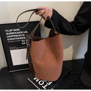 Brown frosted leather bucket bag featuring a spacious design and dark leather strap