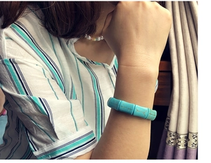 Detailed view of turquoise stretch bracelet with bamboo-shaped beads on a woman's wrist