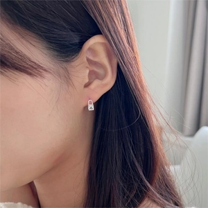Close-up of minimalist sterling silver padlock earrings on a female model ear