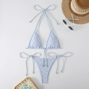 Macro shot of light blue textured bikini set with silver bead details and summer props