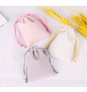 Flat lay of pink, beige, and grey velvet drawstring pouches for jewelry and gifts