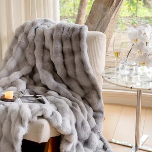 Detailed texture of luxurious light grey faux fur blanket draped over a modern chair