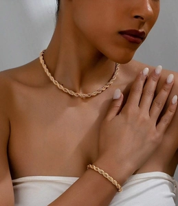 Close-up of gold twisted rope chain necklace and bracelet set on model's neck