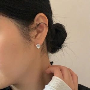Close-up of minimalist silver irregular disc earrings on model with metallic texture