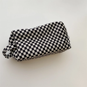 Detail of the checkered velvet makeup bag showing textured fabric and side handle grip