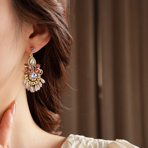 Close-up of vintage gold earrings with colorful rhinestones and elegant pearl tassels