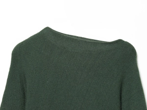 Gros plan du pull en tricot vert forêt montrant la texture fine et le col large