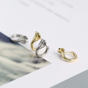 Detailed close-up of cobra head earrings in gold and silver finish with black stone eyes