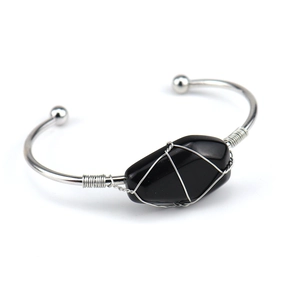 Macro detail of handmade silver wire wrapped raw black crystal stone on an open bangle